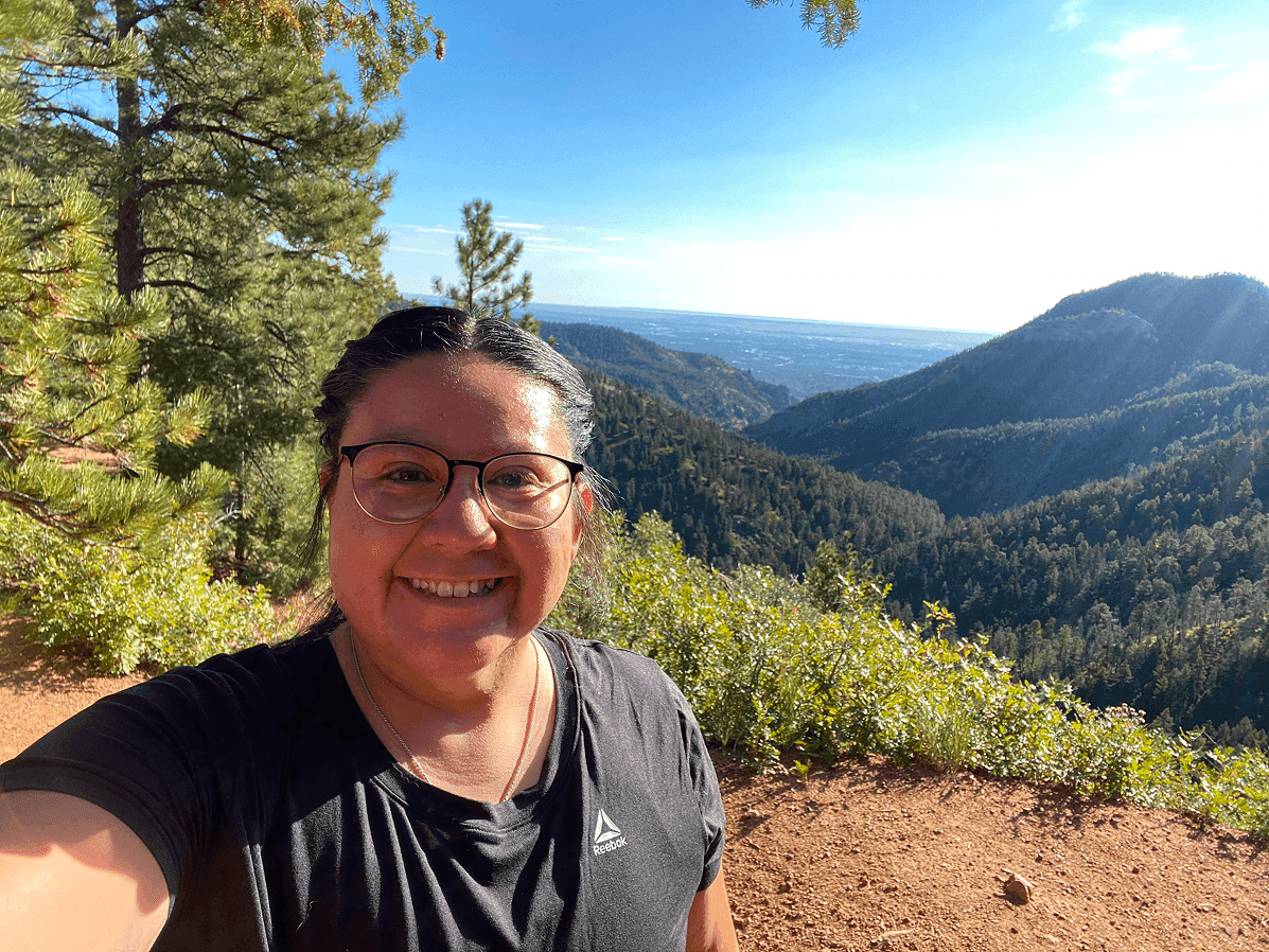 Sabrina on a forested dirt trail in a red jacket
